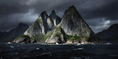 Dramatic coastal peaks of Senja rising vertically above dark ocean waters