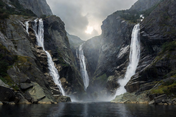 Dramatic vertical rock walls and hanging waterfalls lining the narrow waters of a Norwegian fjord