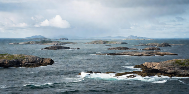 Low-lying archipelago islands of Helgelandskysten across open Norwegian water